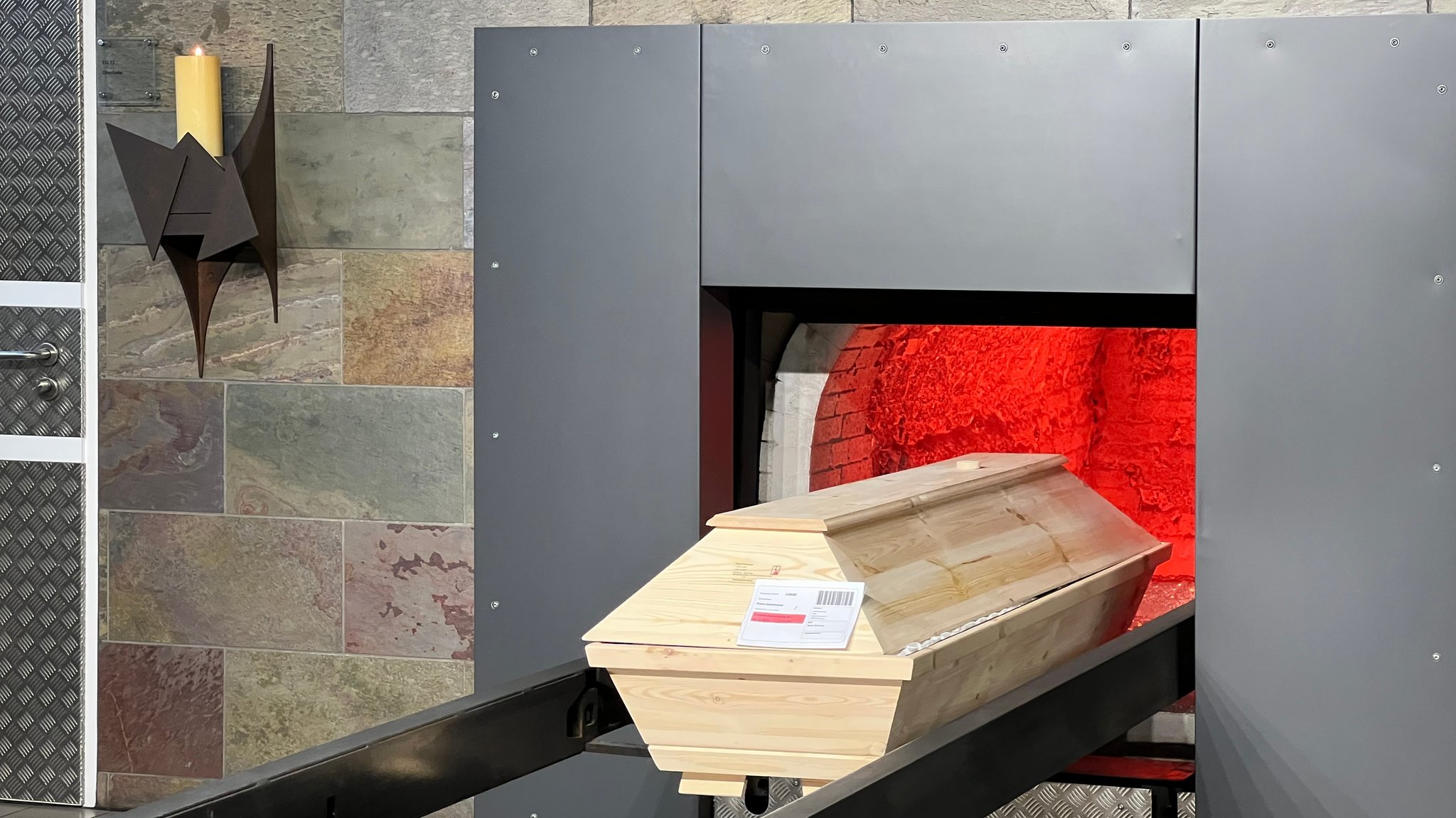 Ein Holzsarg wird im Traunsteiner Krematorium in den Ofen gefahren.