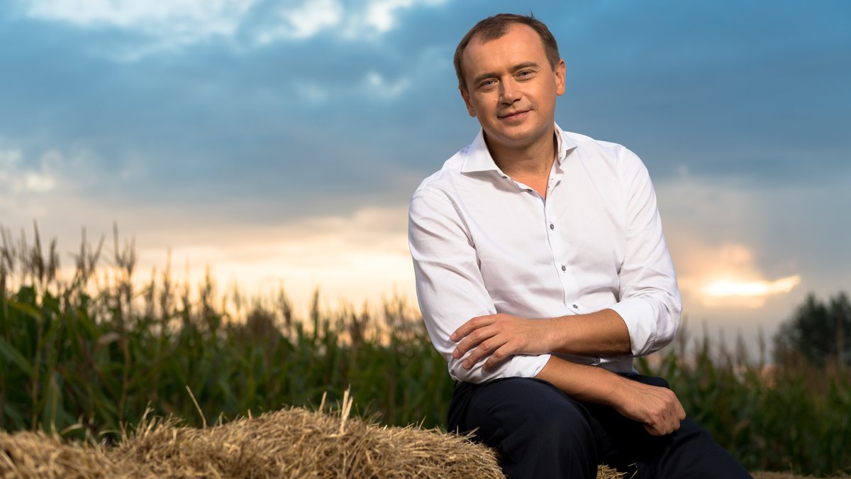 Alex Lissitsa sitzt auf einem Strohballen vor einem Maisfeld.