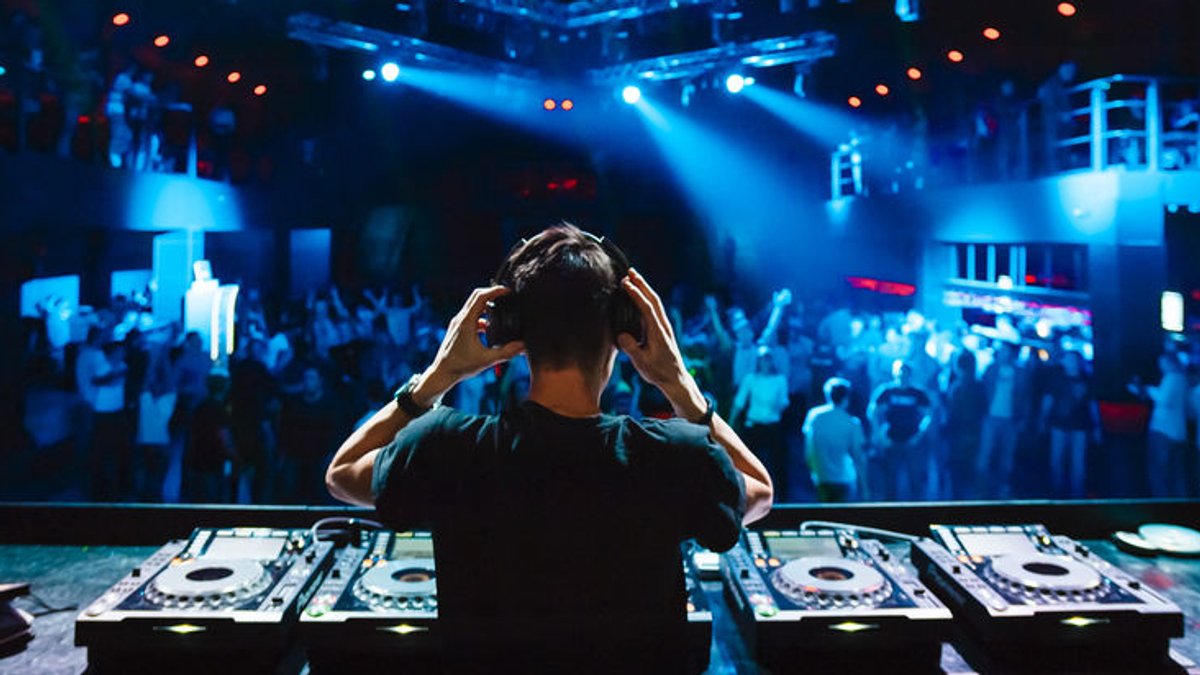 Ein DJ steht in einem Club von seinem DJ-Pult.
