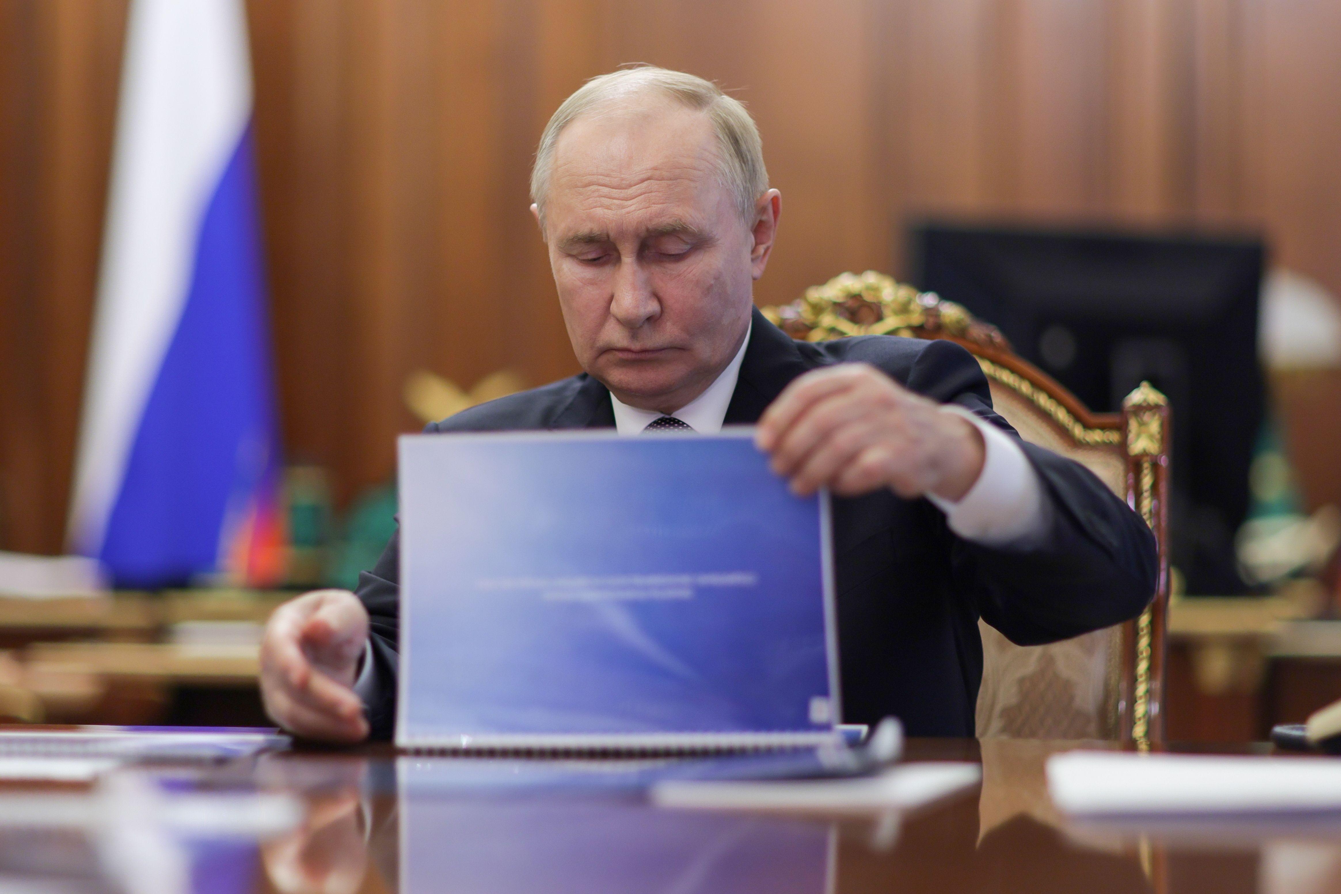 Der russische Präsident blättert durch eine blaue Mappe