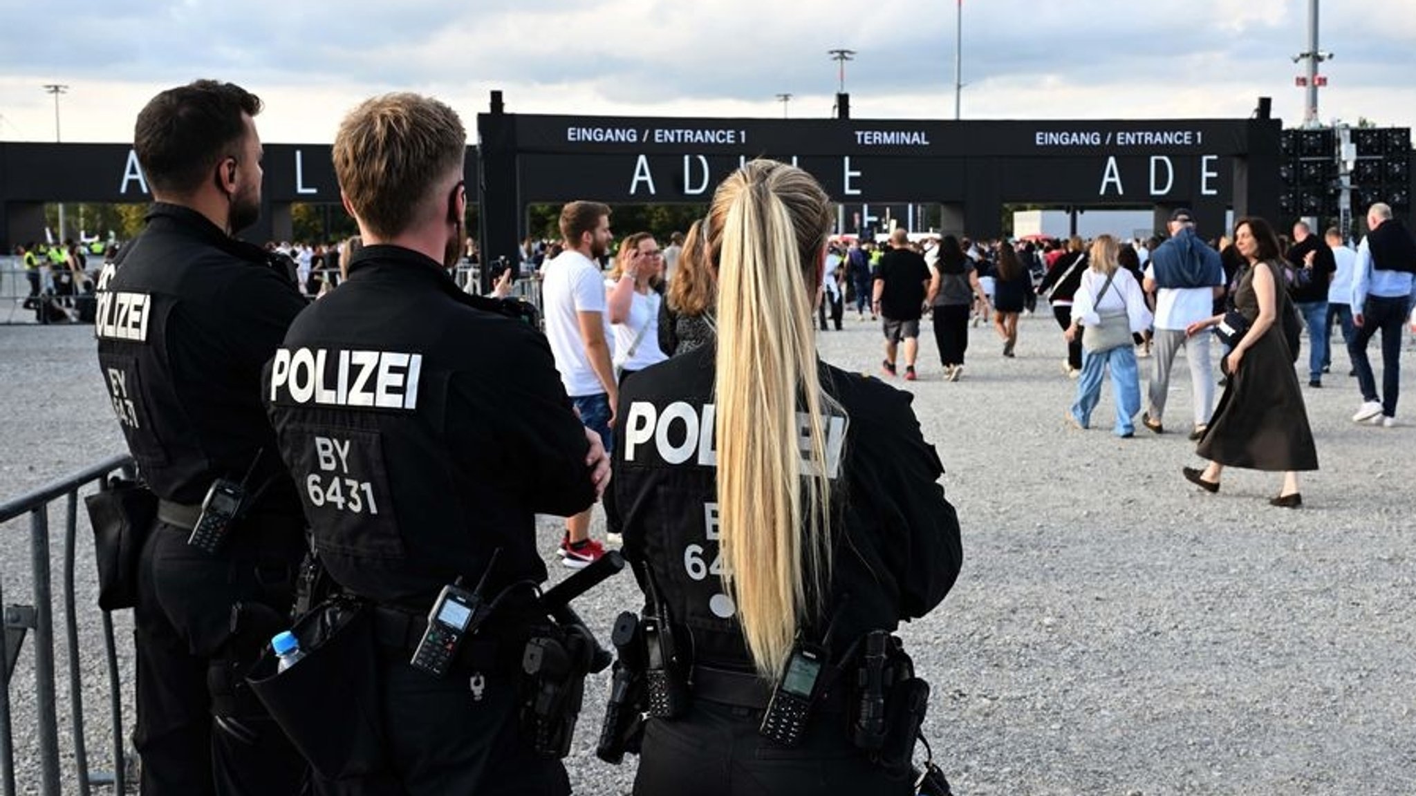 02.08.2024, Bayern, München: Polizisten beobachten Besucher, die auf das Konzert der britischen Sängerin Adele gehen. Foto: Felix Hörhager/dpa +++ dpa-Bildfunk +++