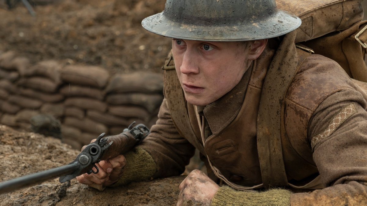 "1917"-Filmszene: Ein junger Soldat mit Gewehr und Stahlhelm im Schützengraben