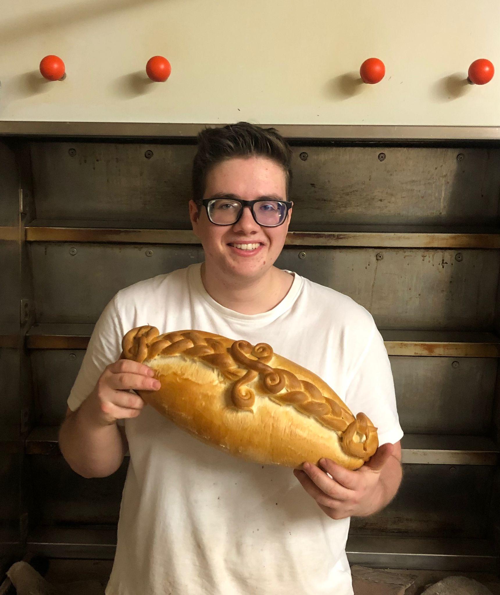 Jungbäcker Nick Deinlein mit einem Brot in den Händen.