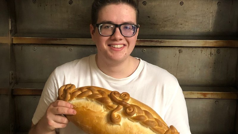 Jungbäcker Nick Deinlein mit einem Brot in den Händen.