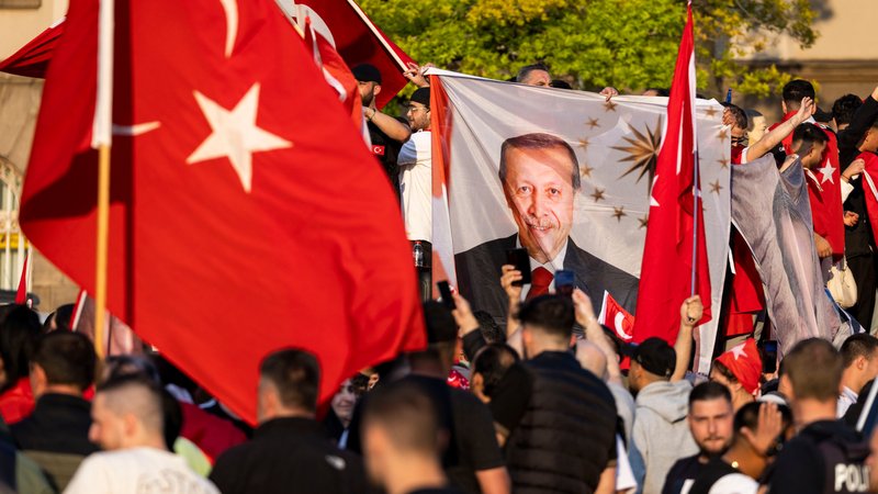 Anhänger des türkischen Präsidenten Erdogan stehen im Duisburger Norden, noch vor dem amtlichen Ergebnis der Stichwahl in der Türkei, mit türkischen Nationalfahnen auf der Straße.
