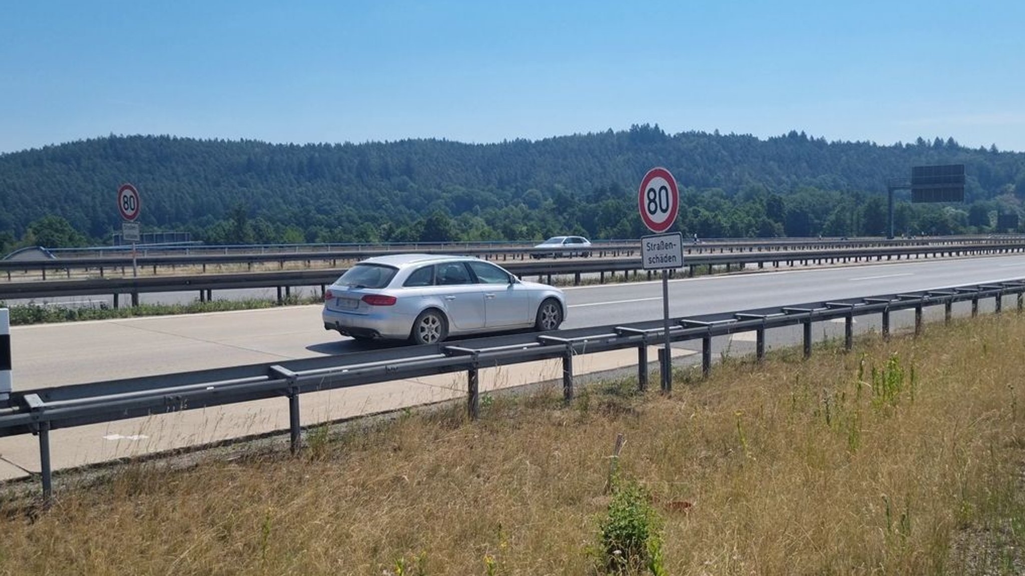 Fahrendes Auto auf alter Autobahn mit Tempolimit-Schild
