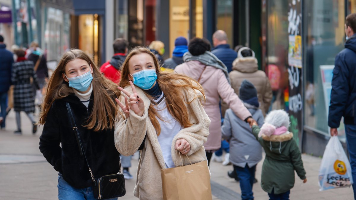 Zwei junge Frauen mit Maske in einer Einkaufsstraße