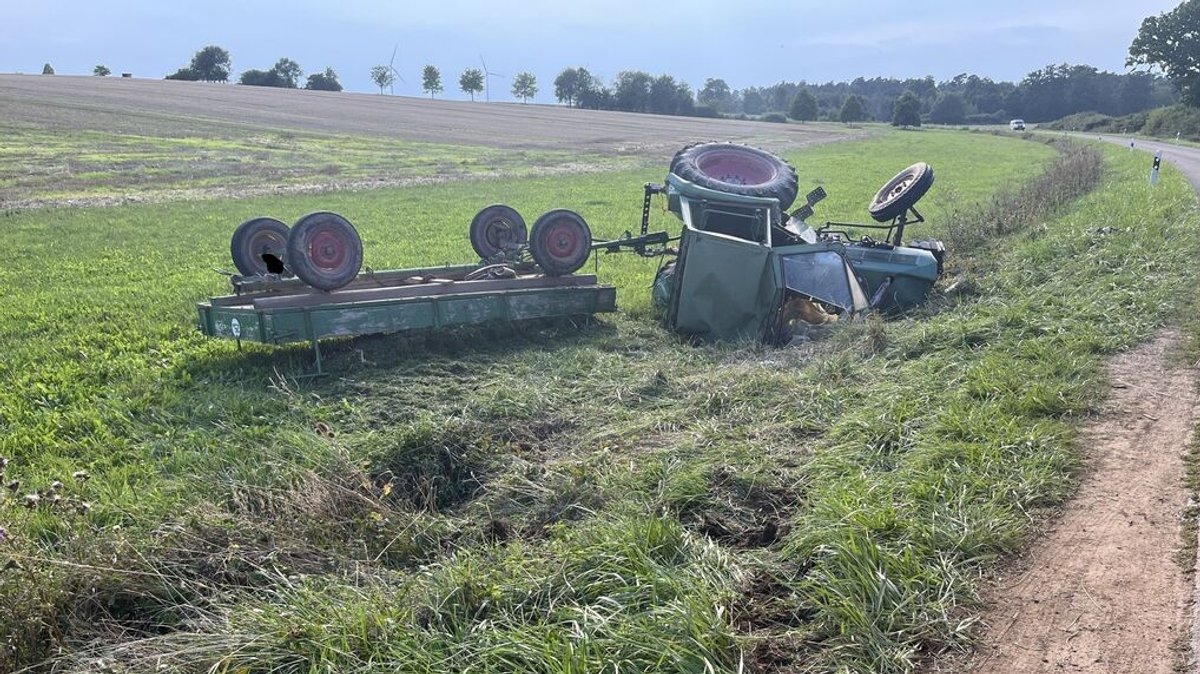 Ein Traktor liegt samt Anhänger in einem Feld. Bei dem Unfall im Landkreis Ansbach im August wurden fünf Menschen teils schwer verletzt. 