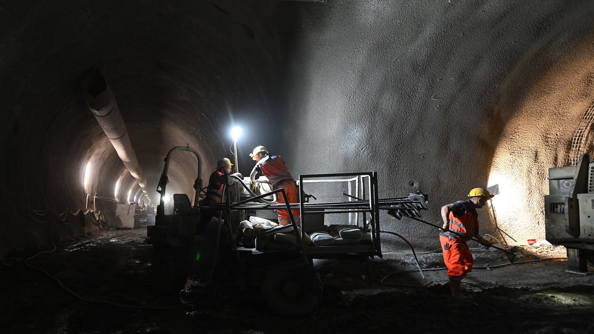 In einer Hauptröhre des Brenner Basistunnels bereiten mehrere Männer eine Sprengung vor. Die Hälfte der Tunnel wurde in das Gestein gesprengt, die andere Hälfte bohrten Tunnelbohrmaschinen aus dem Berg. 