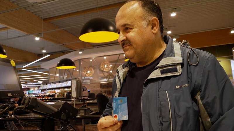 Ein Mann hält in einem Geschäft eine Bezahlkarte in der Hand.