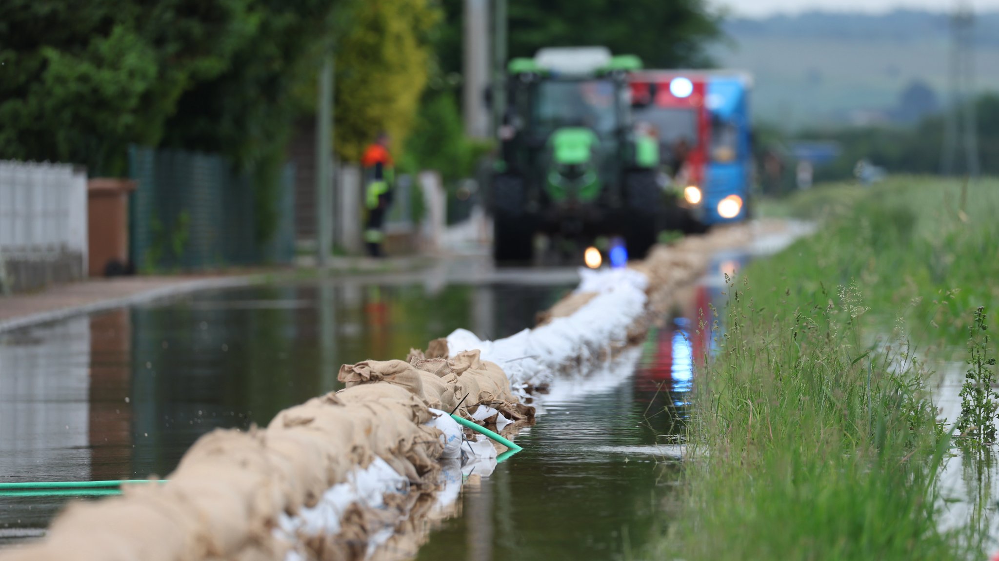 Helfer der Feuerwehr legen am 03.06.24 eine Barriere mit Sandsäcken, um ein Wohngebiet vor dem Hochwasser zu schützen (Archivbild)