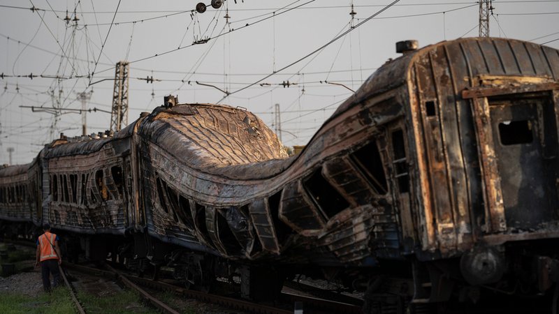 Ein Bahnarbeiter steht neben einem schwer beschädigten Zug nach einem russischen Angriff auf einen Bahnhof am ukrainischen Unabhängigkeitstag. 