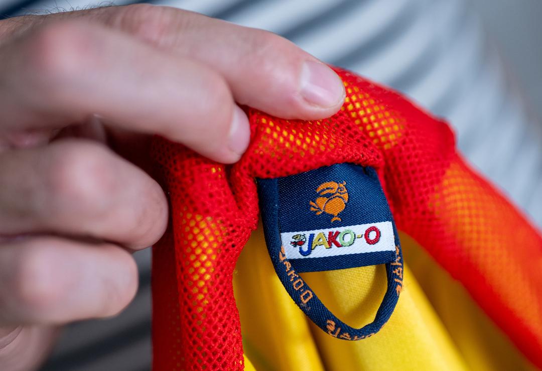 Ein Mann hält eine Kinderjacke der Modemarke Jako-o in der Hand. 