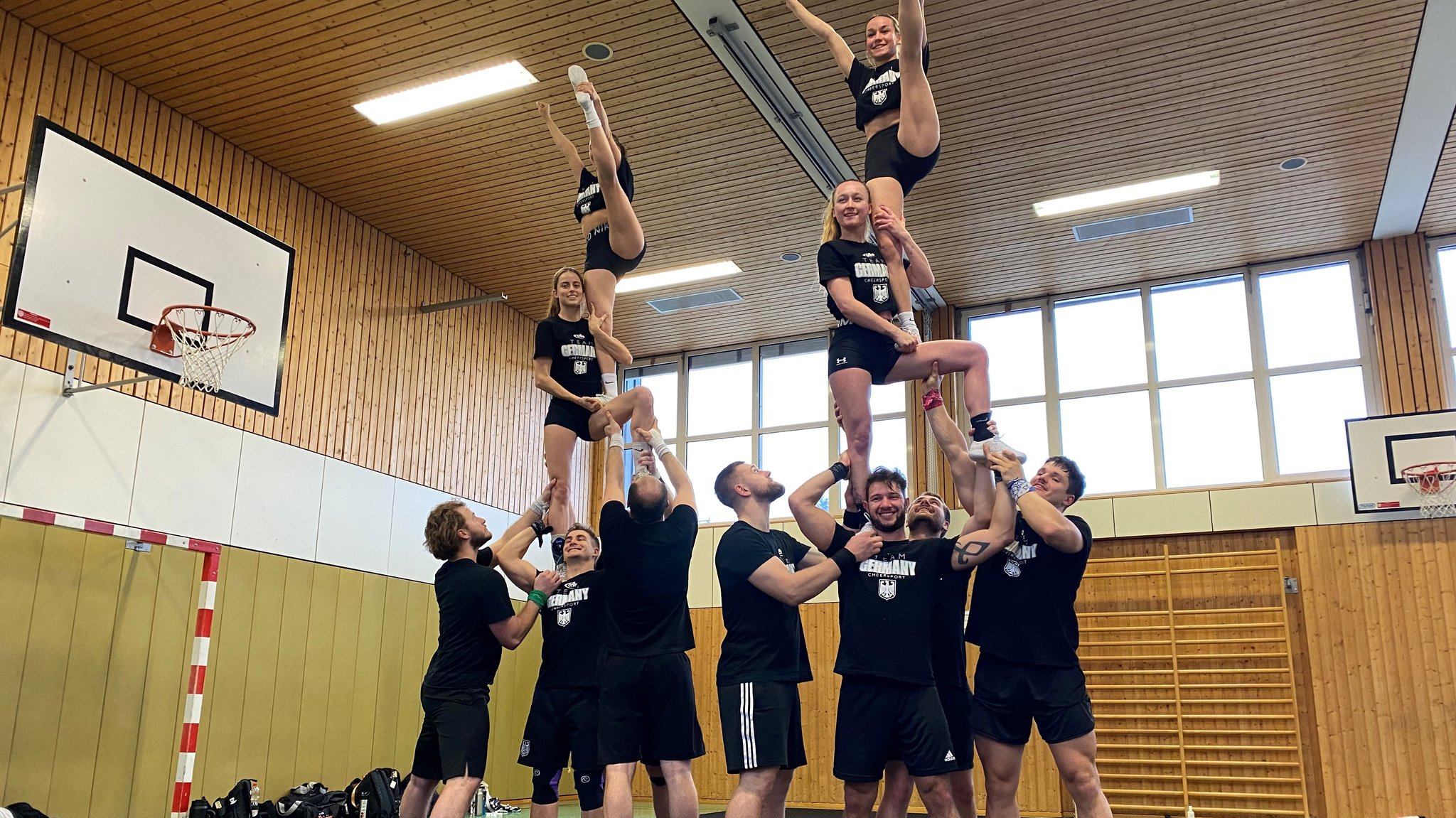 Zwölf Cheerleaderinnen und Cheerleader bilden eine Pyramide.