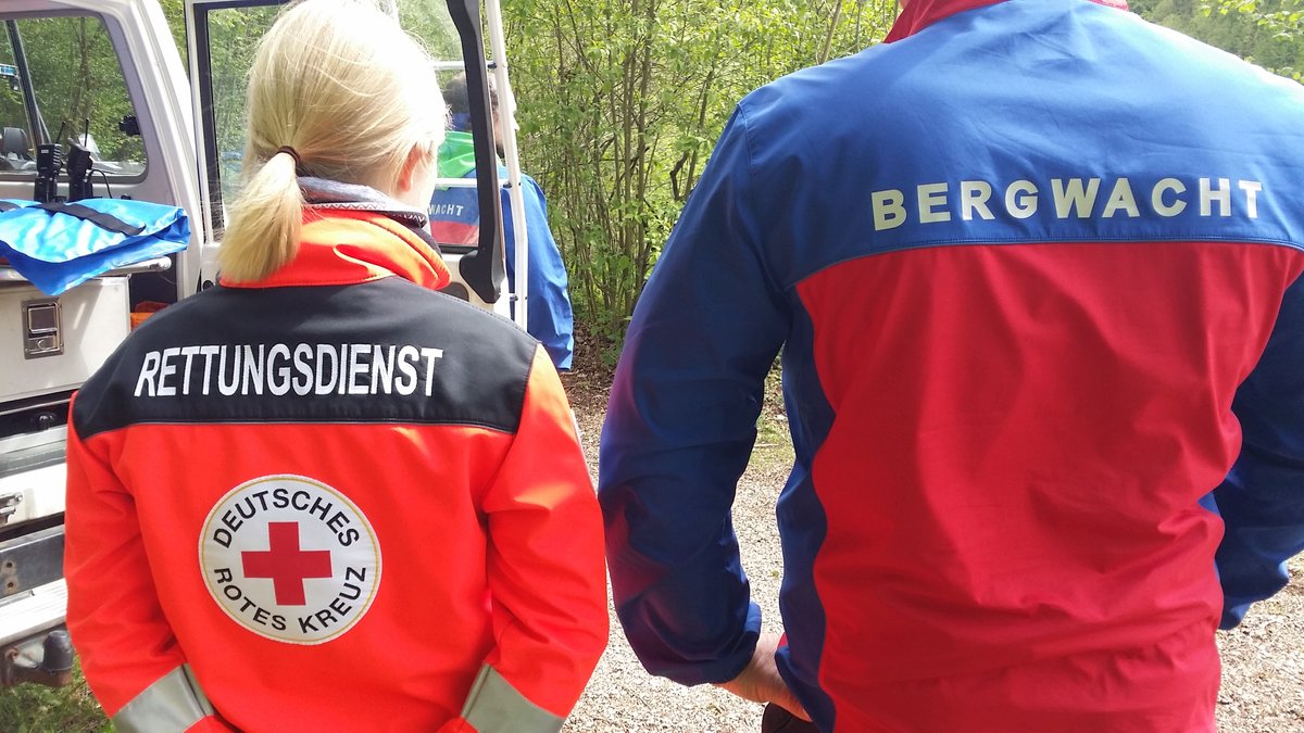 Eine Frau vom Bayerischen Roten Kreuz und ein Mann von der Bergwacht stehen bei einer Übung nebeneinander.
