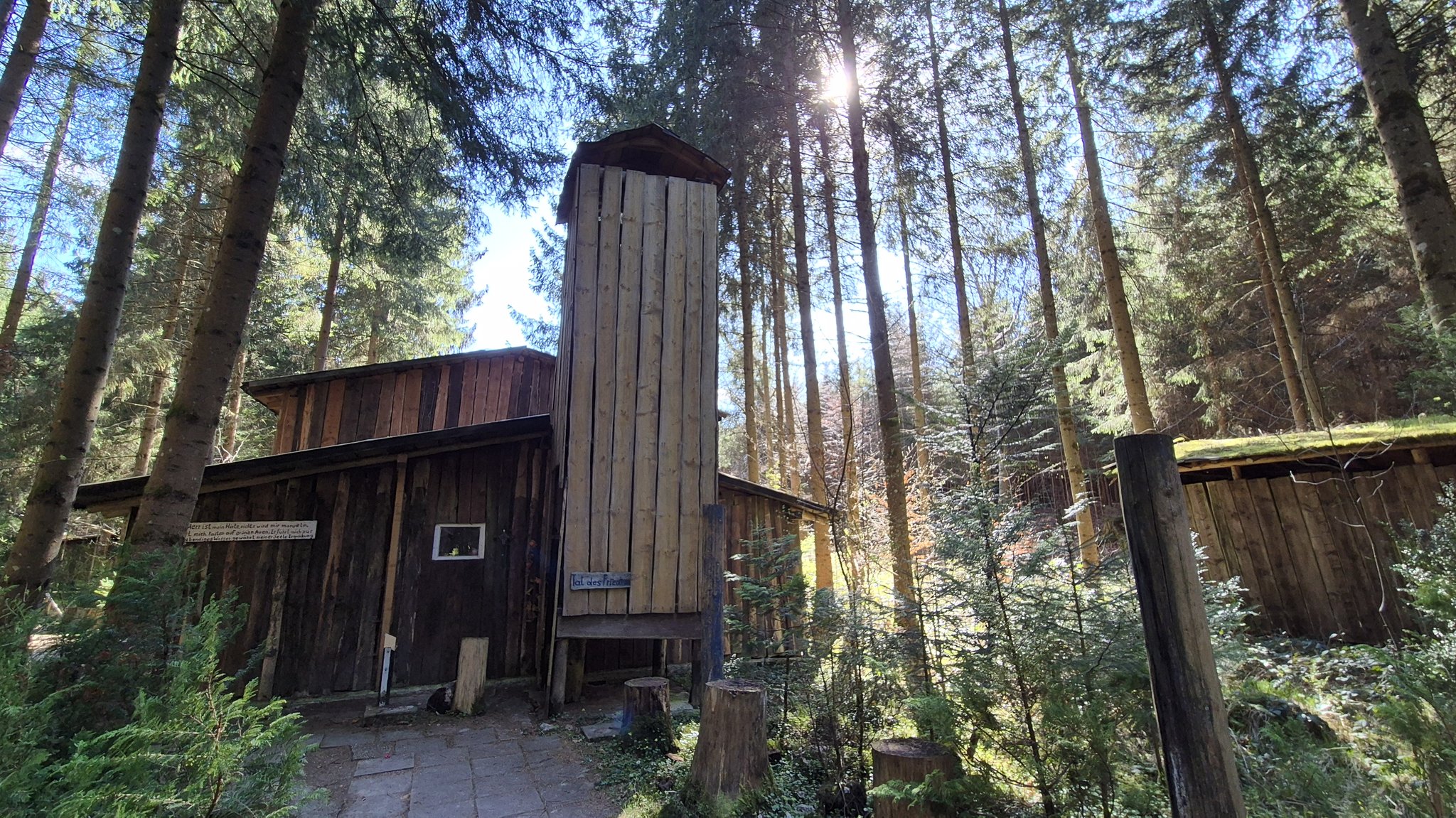 Ein Turm mitten im Wald, daneben Hütten.
