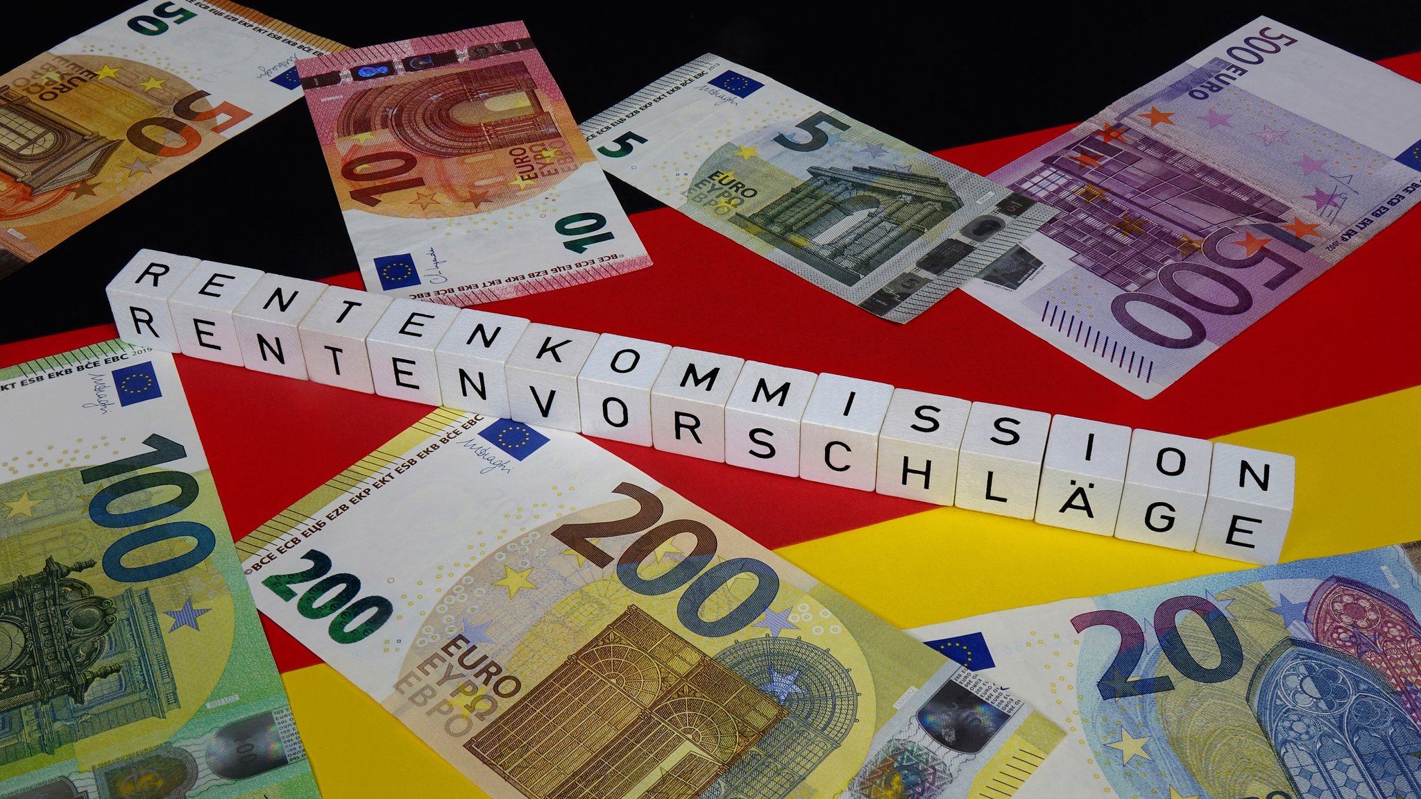 Auf einer Deutschlandfahne befinden sich Geldscheine und Buchstabenwürfel mit Schriftzügen Rentenkommission und Rentenvorschläge (Fotomontage) | Bild: picture alliance / ZB | Sascha Steinach Auf einer Deutschlandfahne befinden sich Geldscheine und Buchstabenwürfel mit Schriftzügen Rentenkommission und Rentenvorschläge (Fotomontage)