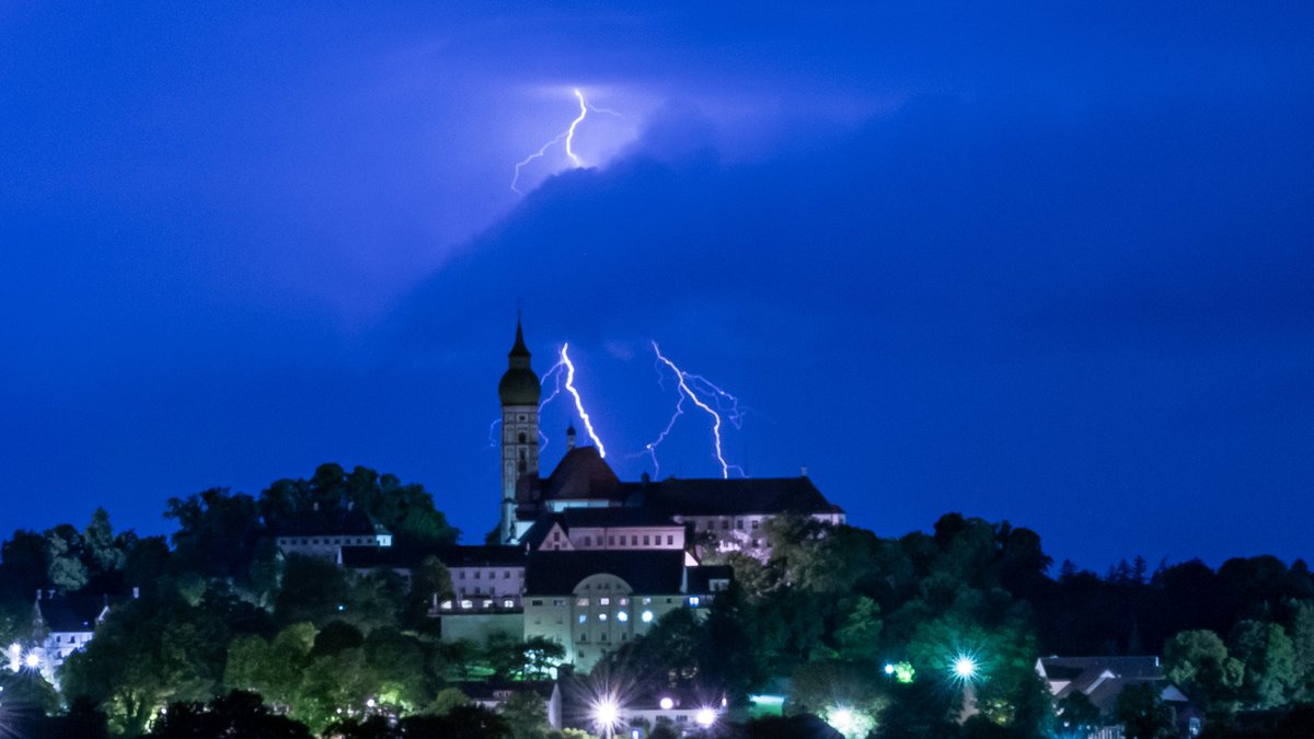 Ein Gewitter entlädt sich mit Blitz und Donner hinter der Kulisse des Kloster Andechs.