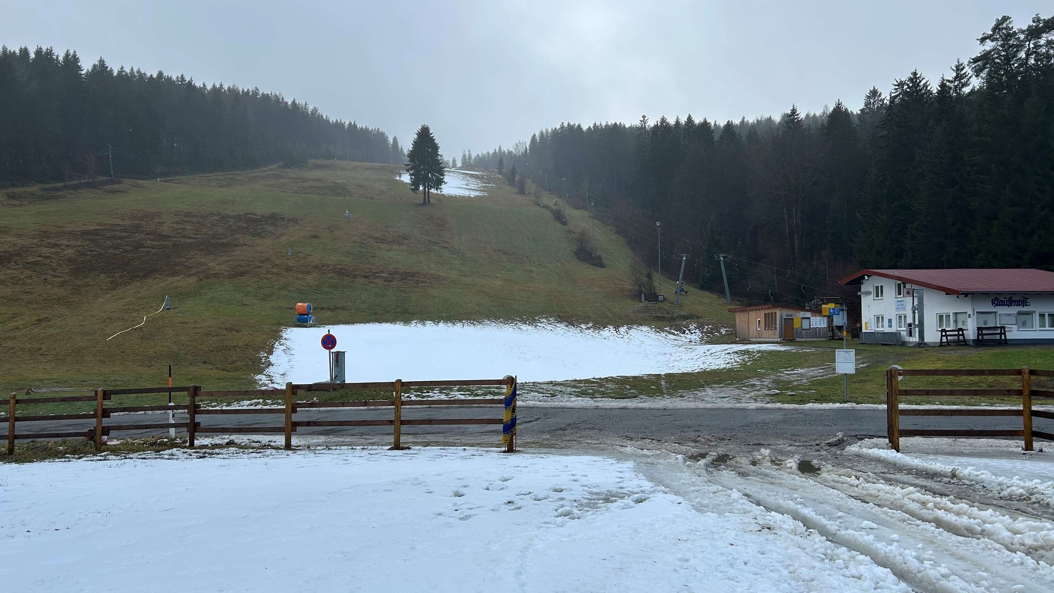 Ein Skihang mit nur wenig Schnee und vielen braun-grünen Flächen.