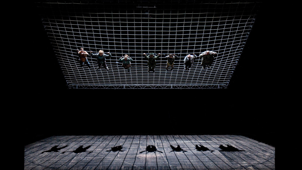 Sieben Menschen in einem großen Netz, am Boden ihr Schatten