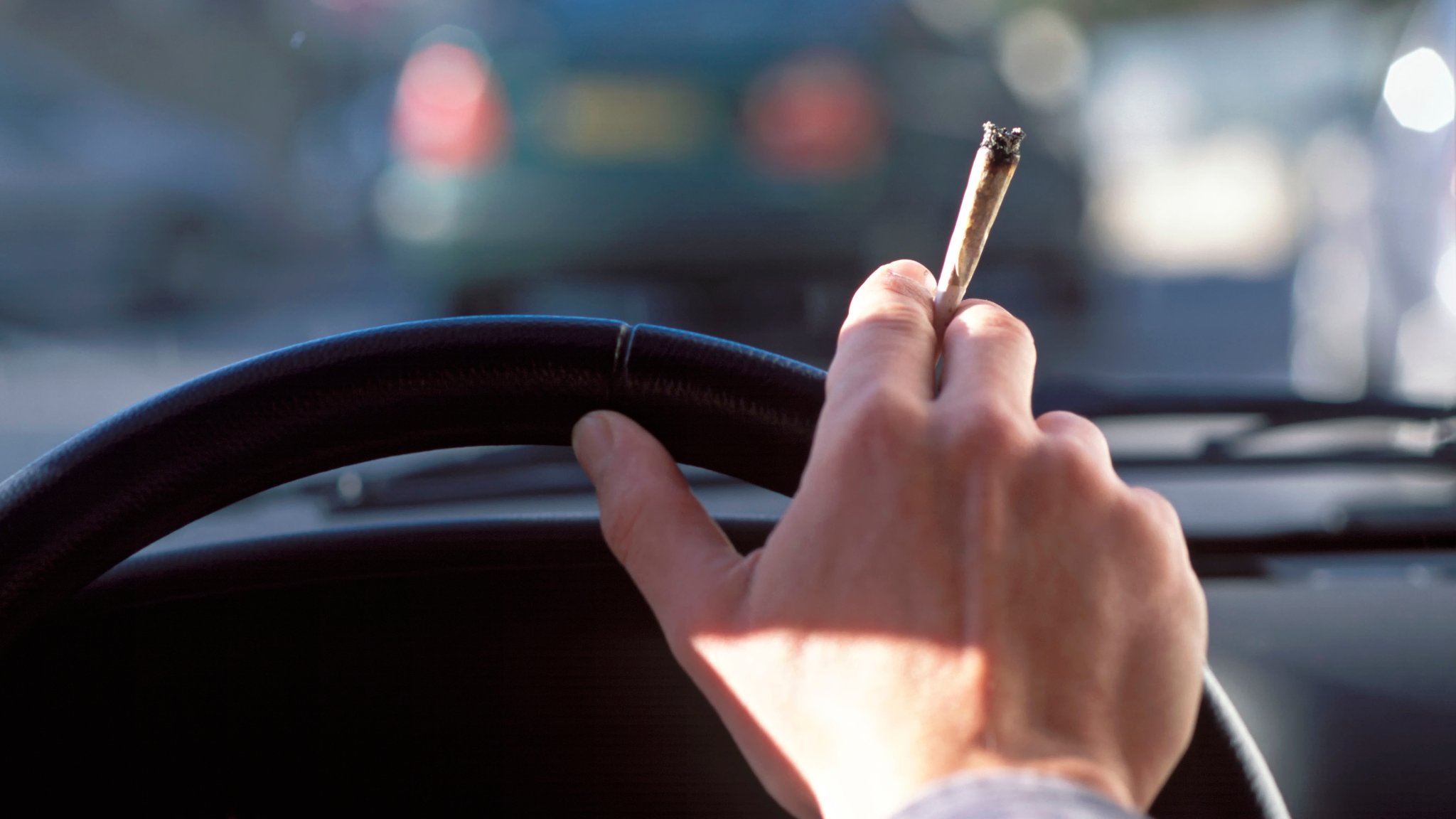 Ein Mann mit Joint am Autolenkrad