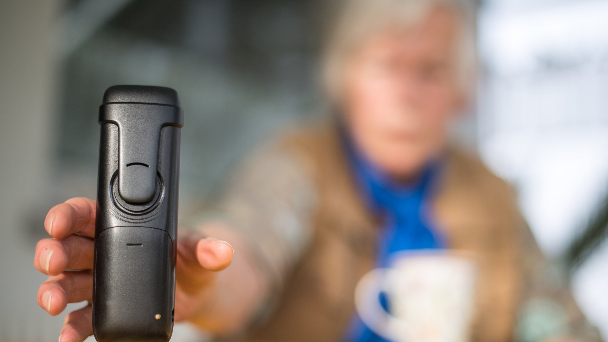 Eine alte Frau sitzt an einem Tisch und greift zum Telefon (Symbolbild)