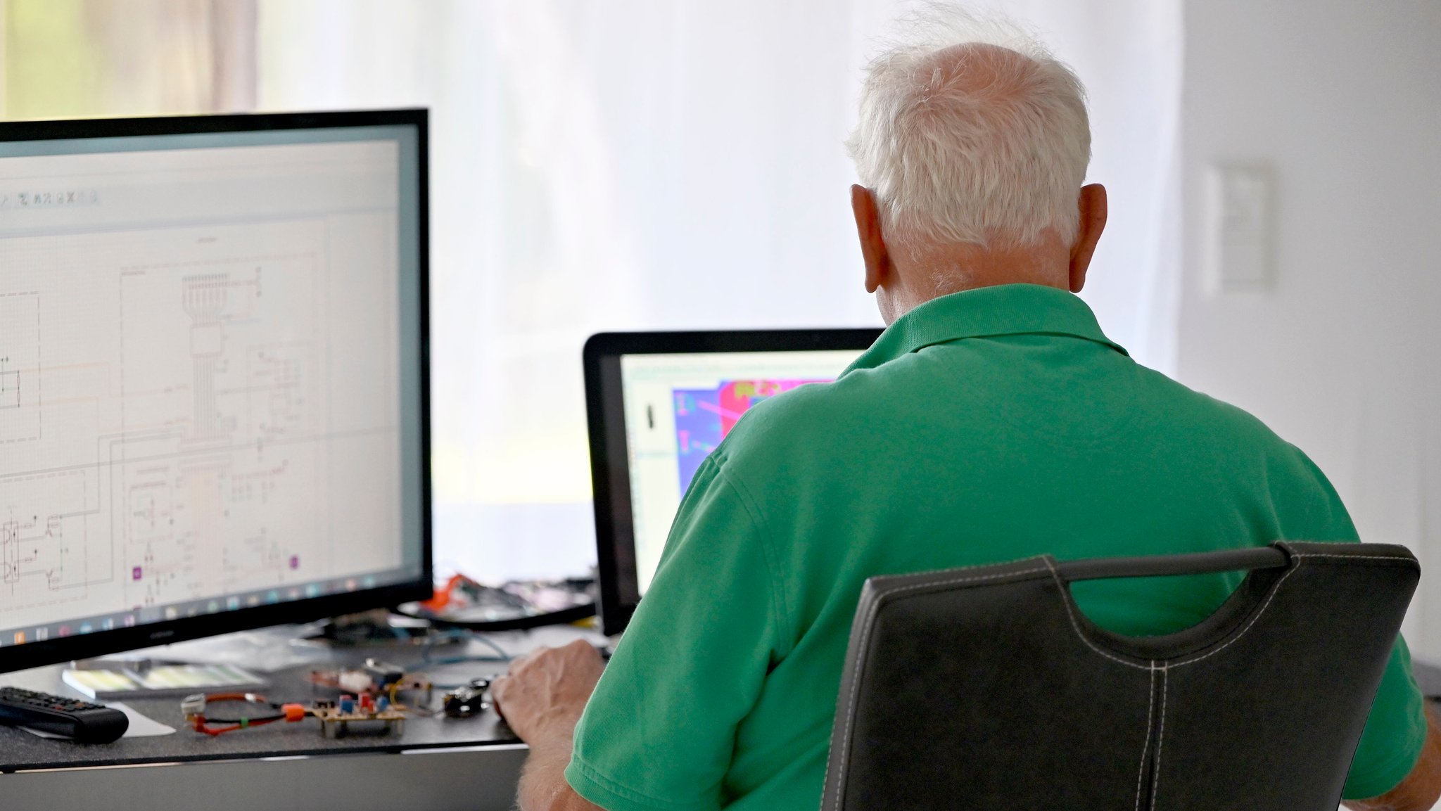 Ein Senior vor Bildschirmen im Homeoffice