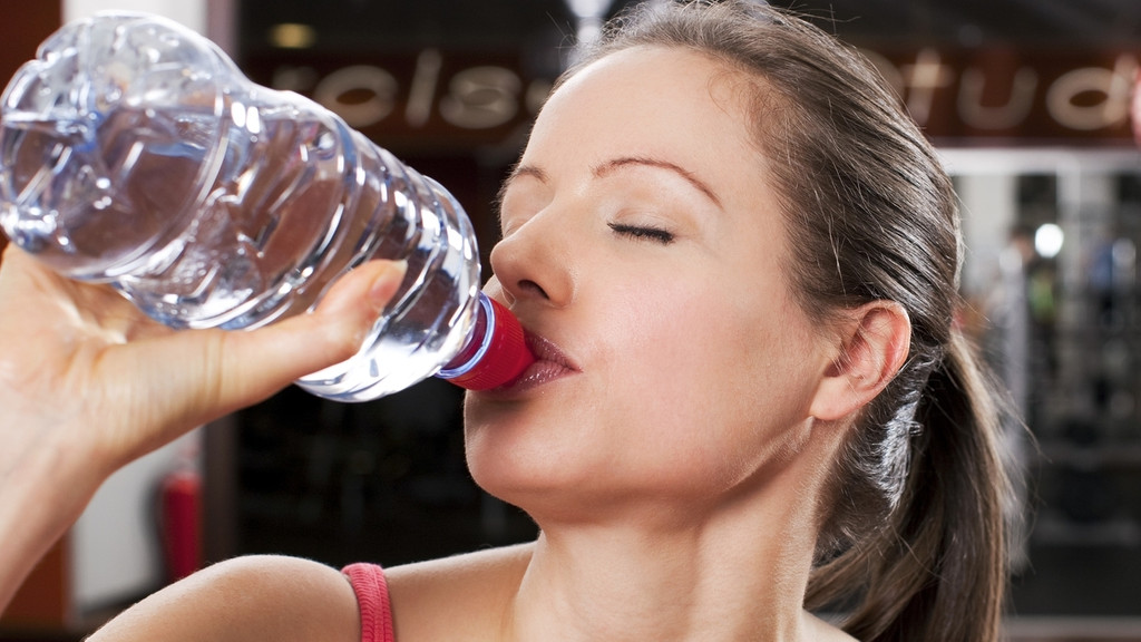 Frau trinkt Wasser im Fitnessstudio