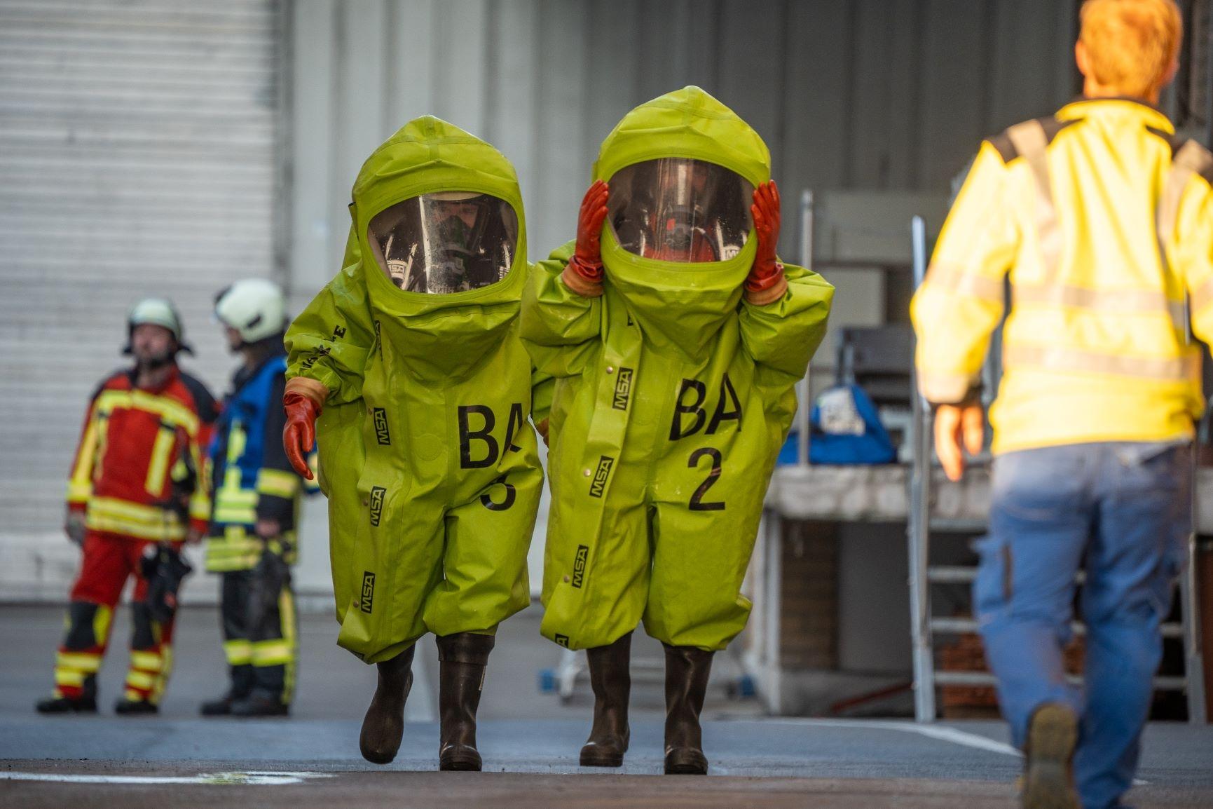 Einsatzkräfte in grünen Chemikalienschutzanzügen.