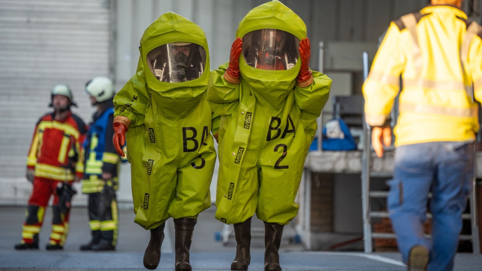 Einsatzkräfte in grünen Chemikalienschutzanzügen.