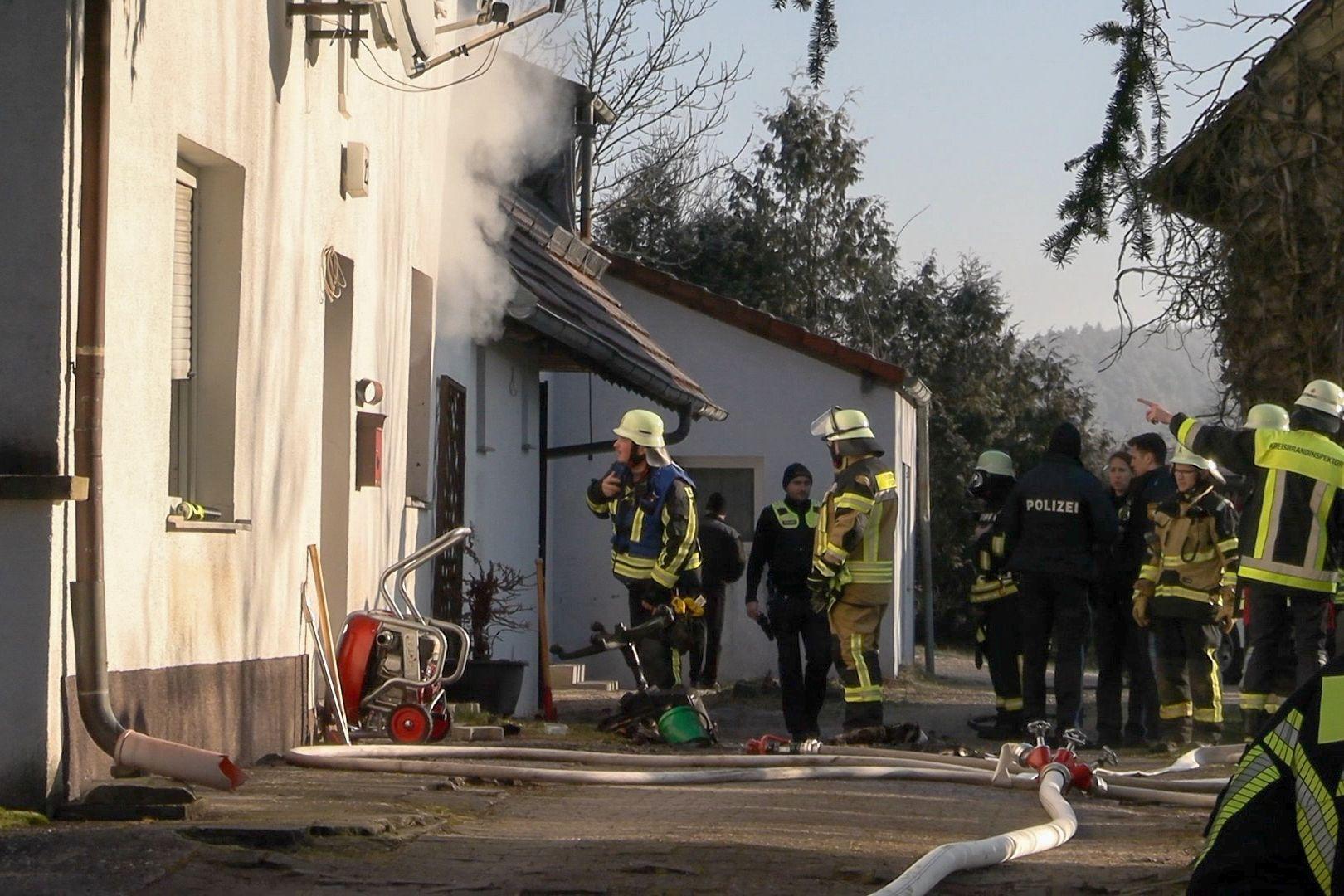 Feuerwehrkräfte vor dem Haus aus dem Rauch quillt