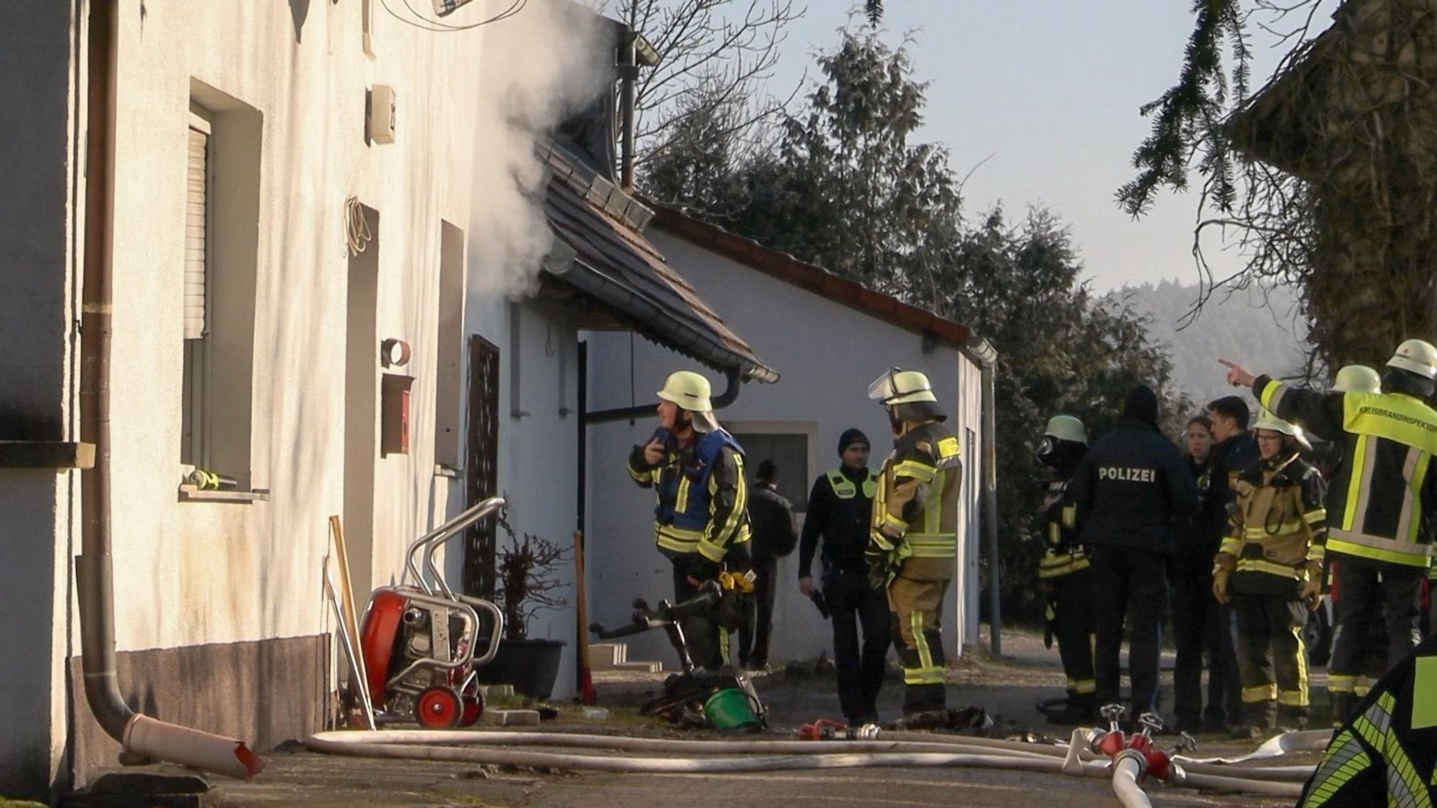 Feuerwehrkräfte vor dem Haus aus dem Rauch quillt