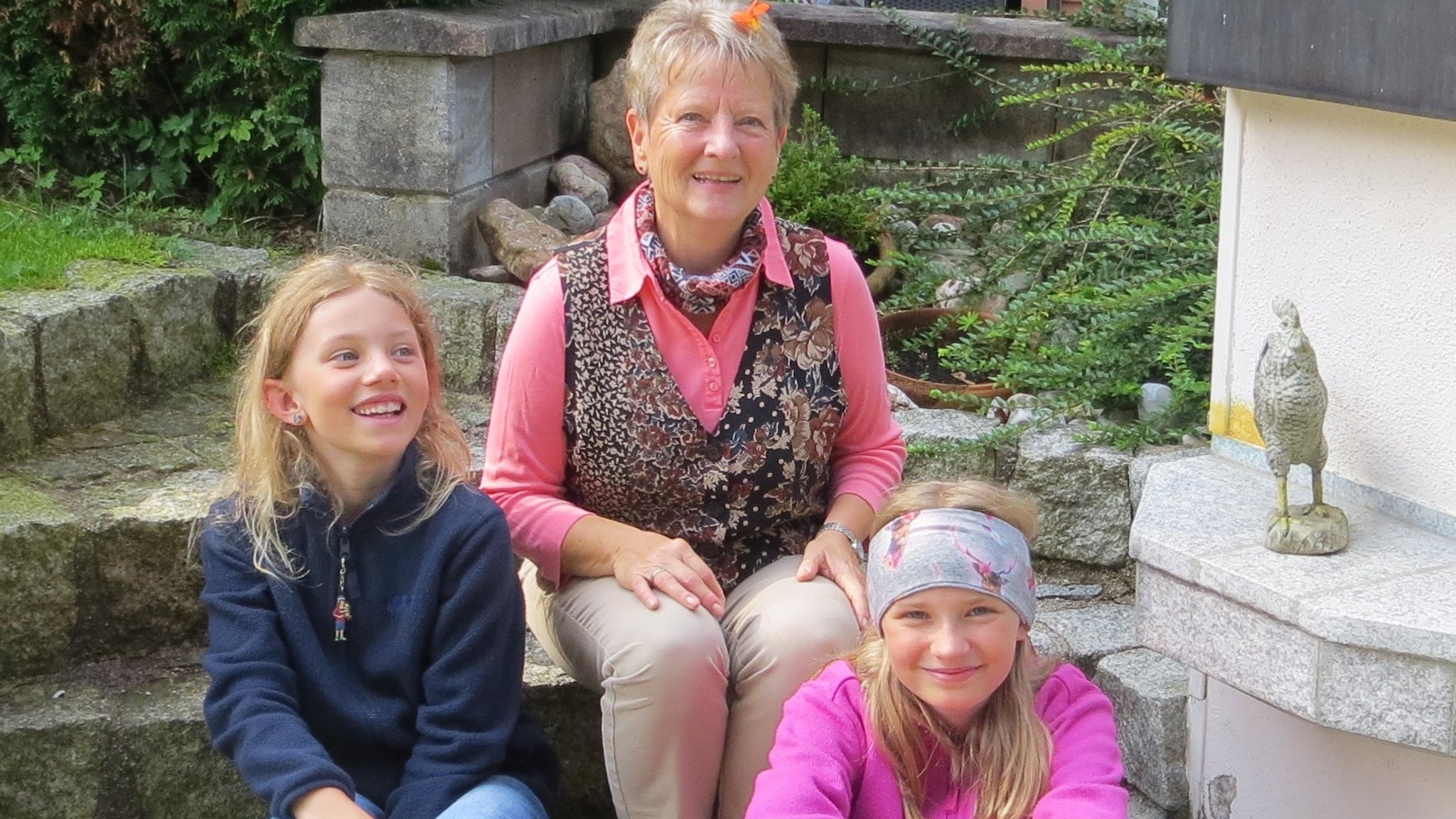 Bärbel Steinbacher sitzt mit den beiden Mädchen auf einer Steintreppe.