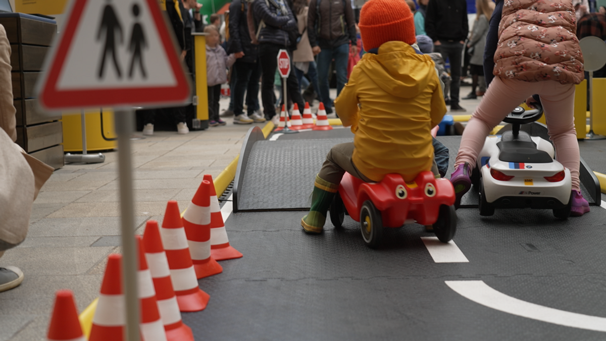 Kinder fahren mit Bobbycars in einem aufgebauten Verkehrsparcours mit Hütchen und Verkehrsschildernschildern