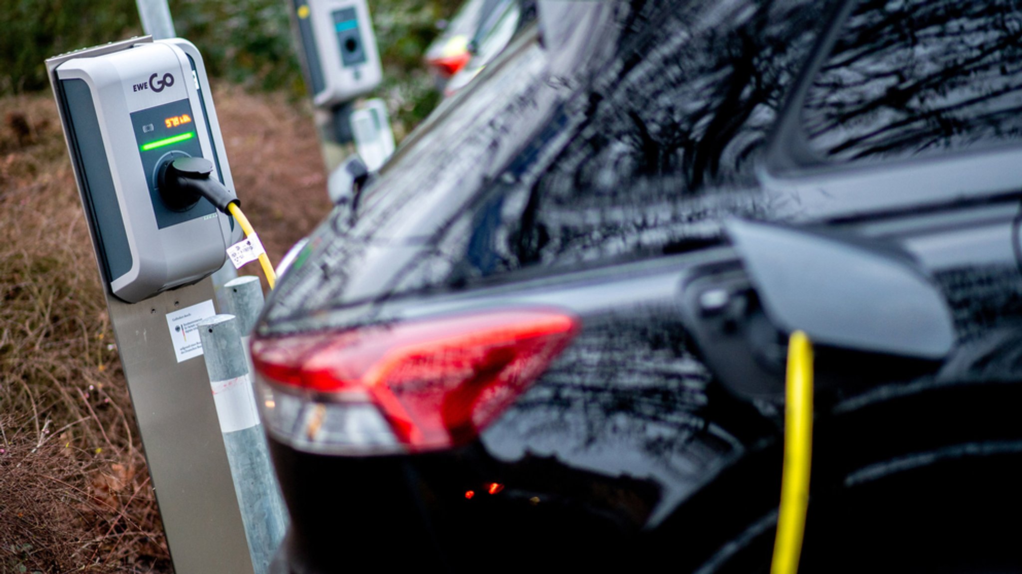 Ein Elektroauto wird an einer Ladestation auf einem Parkplatz geladen.