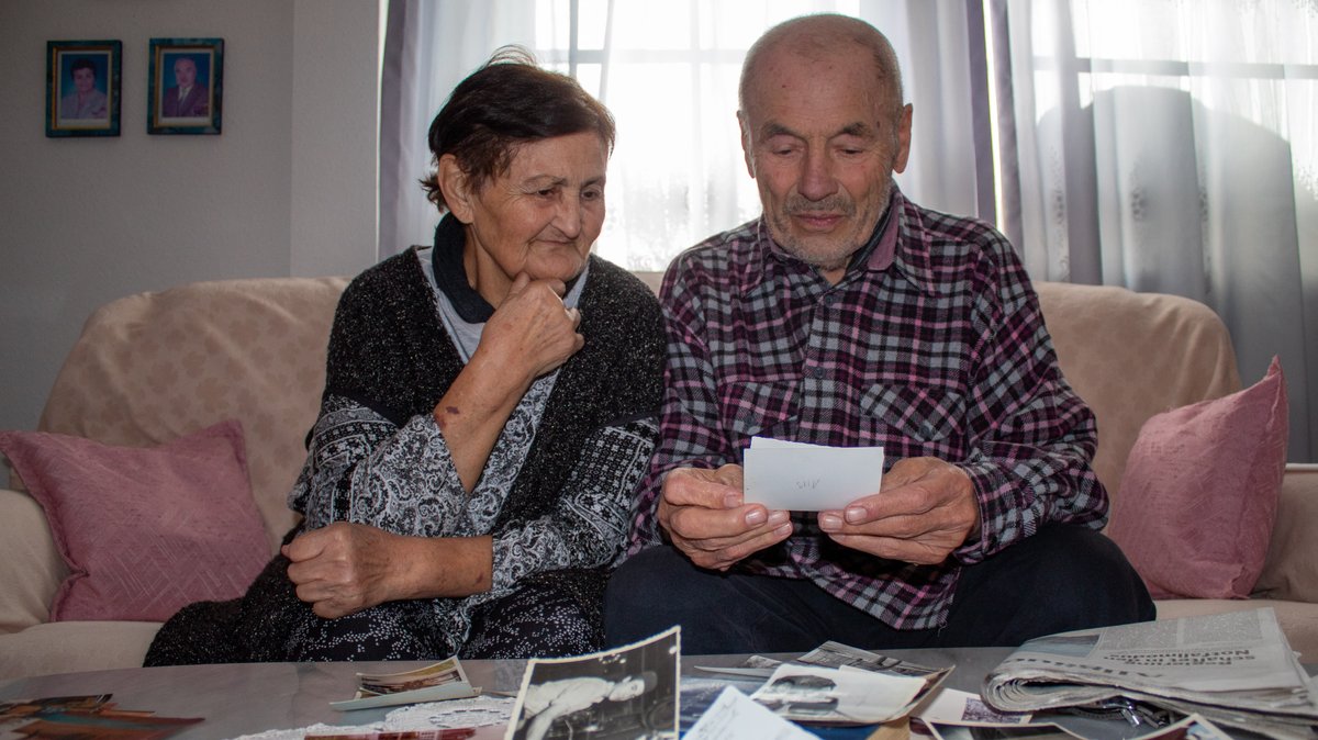 Dursun Düzer sitzt mit seiner Frau Sevim auf dem Sofa und schaut Fotos an