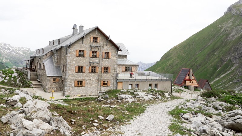 Eine imposante, mehrstöckige Berghütte vor Allgäuer Alpenkulisse im wolkigen Frühsommer. Im Hintergrund sind schneebedeckte Gipfel zu erkennen. | Bild: BR / Louis Seibert Eine imposante, mehrstöckige Berghütte vor Allgäuer Alpenkulisse im wolkigen Frühsommer. Im Hintergrund sind schneebedeckte Gipfel zu erkennen.