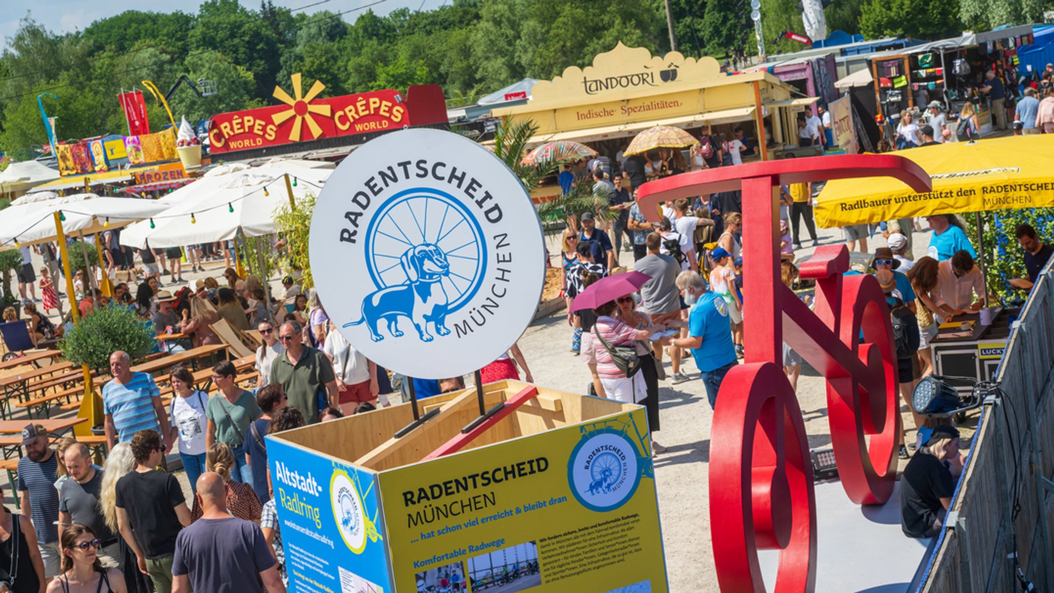 Besucher des Tollwood-Sommerfestivals laufen durch den Olympiapark Süd.