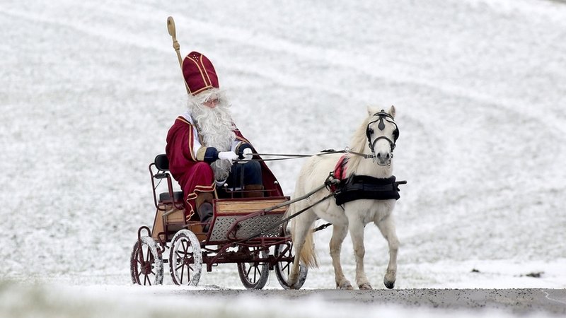 Der heilige Nikolaus fährt mit einer Kutsche durch eine weiße Winterlandschaft.