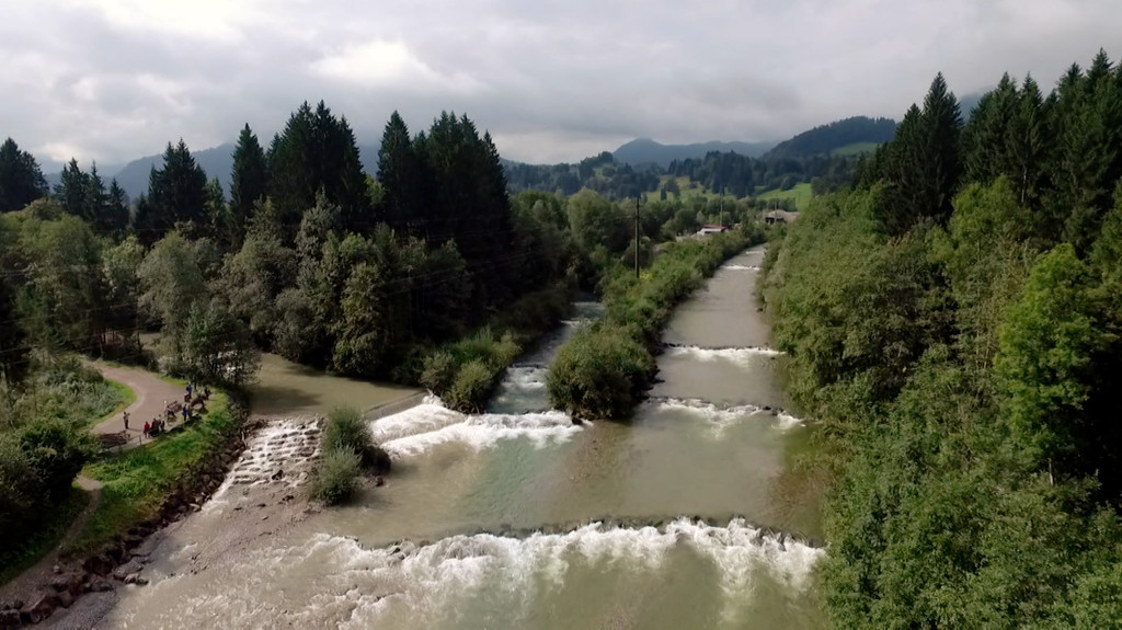 Ein Luftbild eines Flusses, umgeben von Bäumen und Bergen.