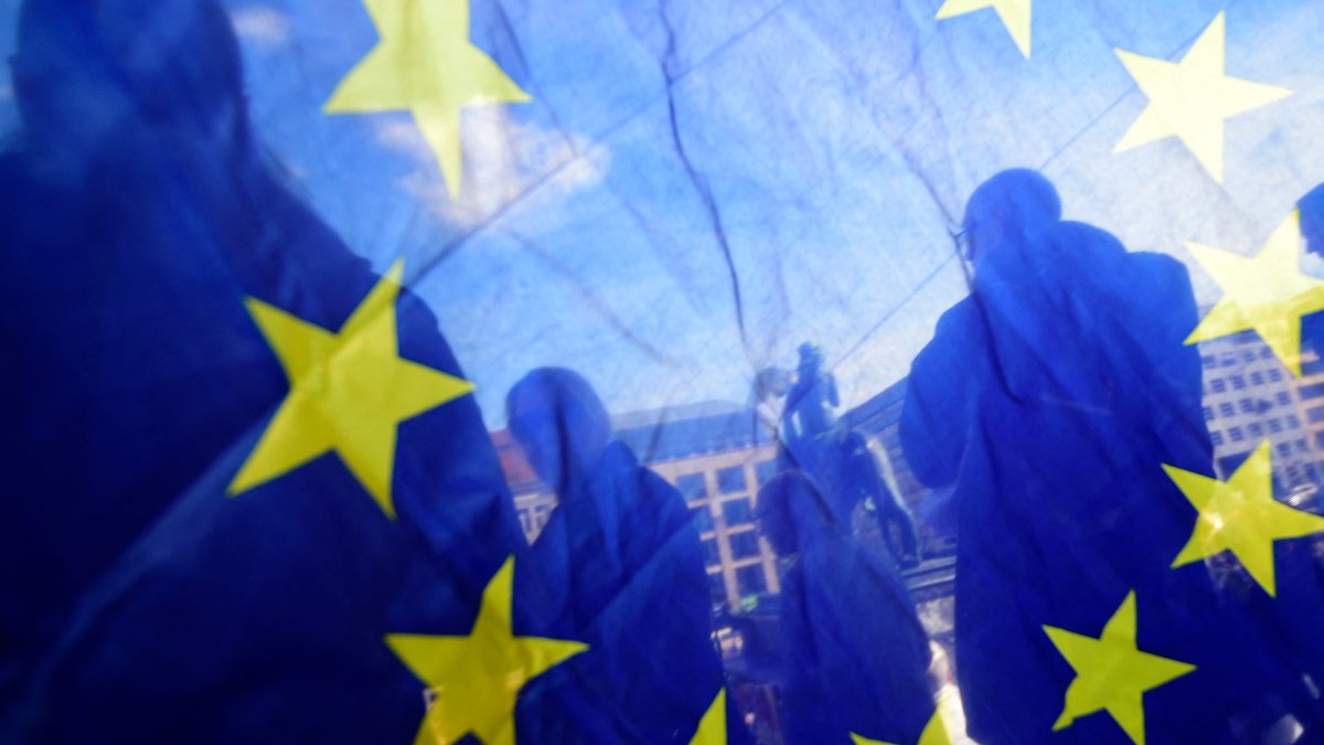 Das Foto zeigt Menschen durch eine Europaflagge hindurch.