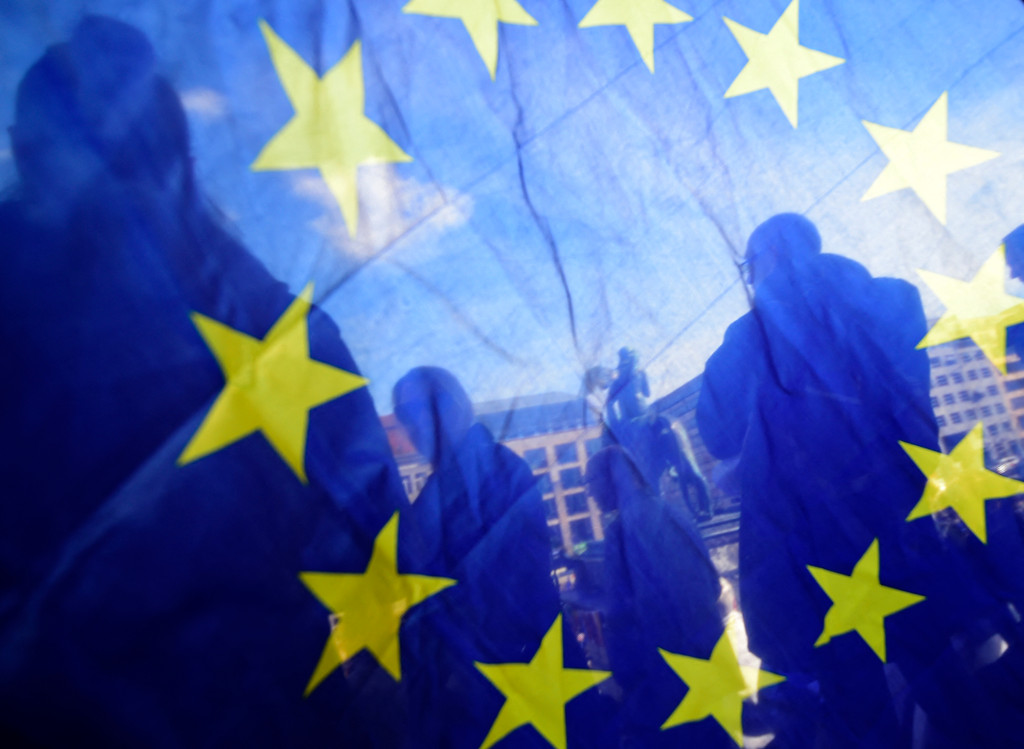 Das Foto zeigt Menschen durch eine Europaflagge hindurch.