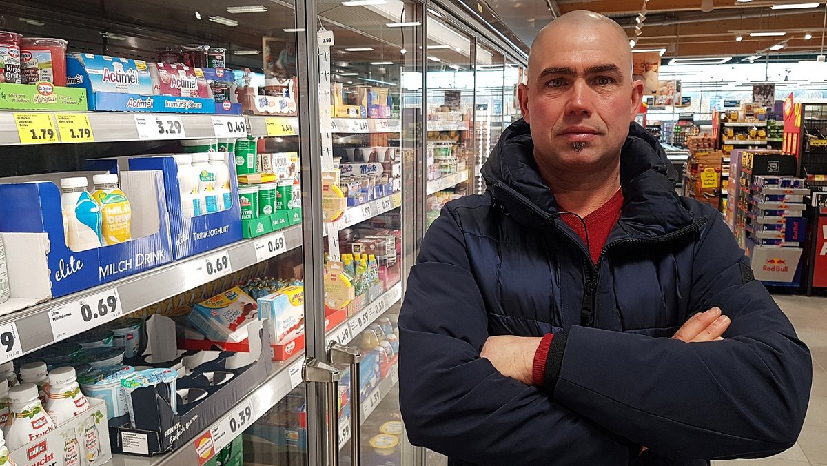 Der bayerische Milchbauer Martin Stadler steht vor dem Kühlregal mit Milchprodukten eines Supermarktes.