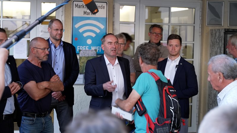 Hubert Aiwanger steht zwischen Männern, die ihn kritisch anschauen. Hinter ihm sind seine Personenschützer. | Bild: BR / Mic Bassing Hubert Aiwanger steht zwischen Männern, die ihn kritisch anschauen. Hinter ihm sind seine Personenschützer.