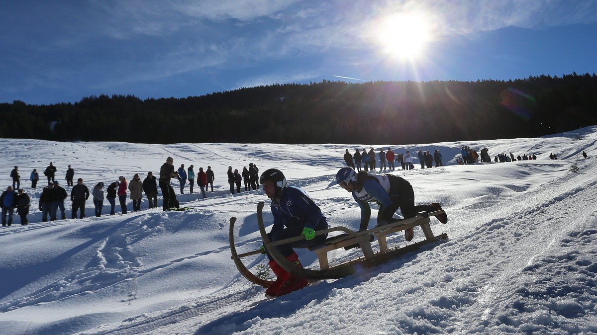 Ein Zweierteam vor Zuschauern auf der Piste des Schlittenrennens in Bad Hindelang im Oberallgäu