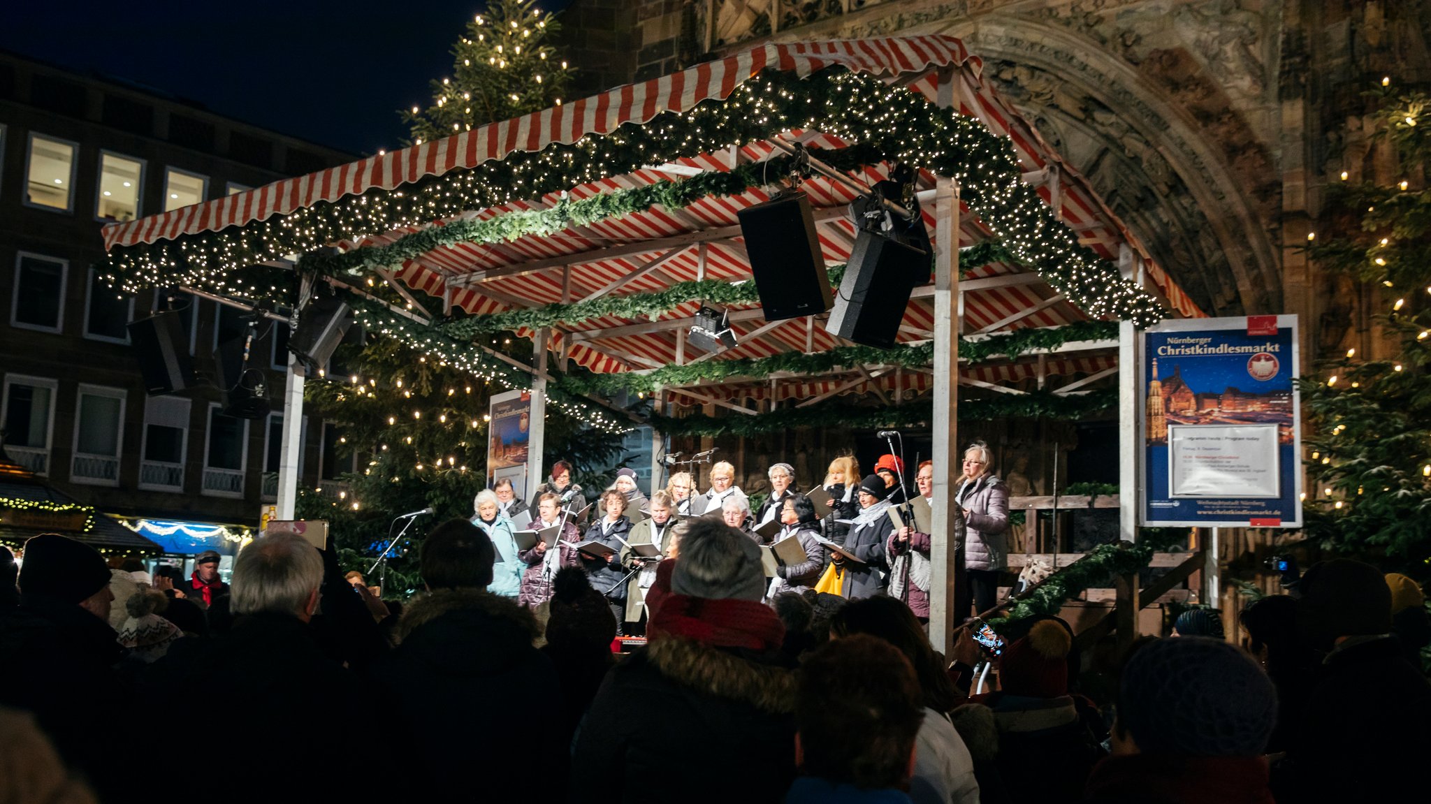 Ein Chor singt am Nürnberger Christkindlesmarkt vor der Nürnberger Frauenkirche auf der Bühne | Bild: BR/Philipp Kimmelzwinger Ein Chor singt am Nürnberger Christkindlesmarkt vor der Nürnberger Frauenkirche auf der Bühne