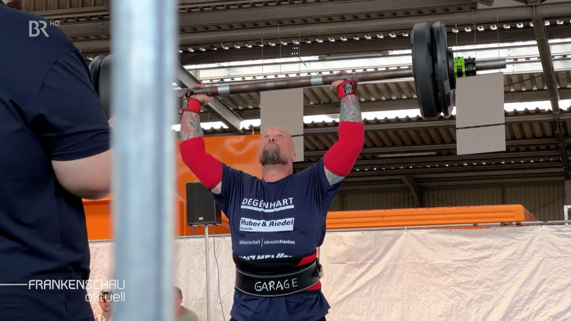 Ein Mann stämmt eine Langhantel über den Kopf.