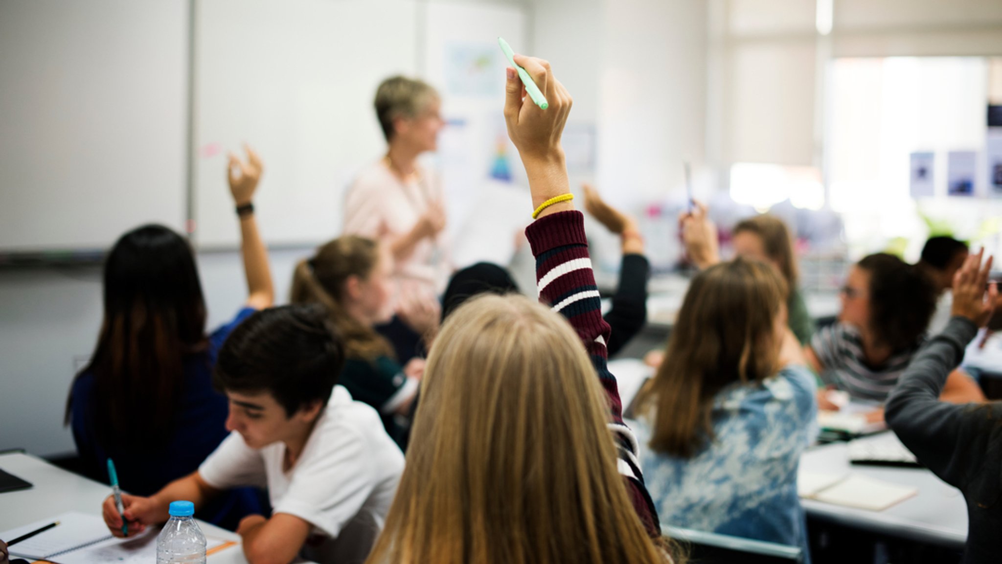 Klassenzimmer (Symbolbild): Eine Gruppe von Schülern, die sich im Unterricht melden.