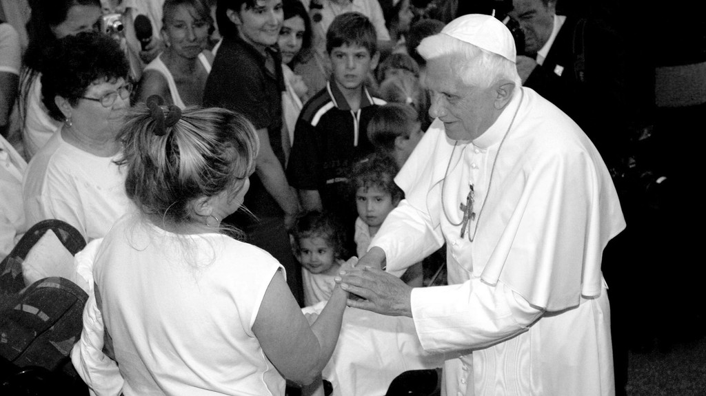Archiv: Papst Benedikt XVI. wendet sich am 13.09.2006 in Pentling vor seinem Privathaus an eine Gläubige neben einem Kind mit Behinderung. 