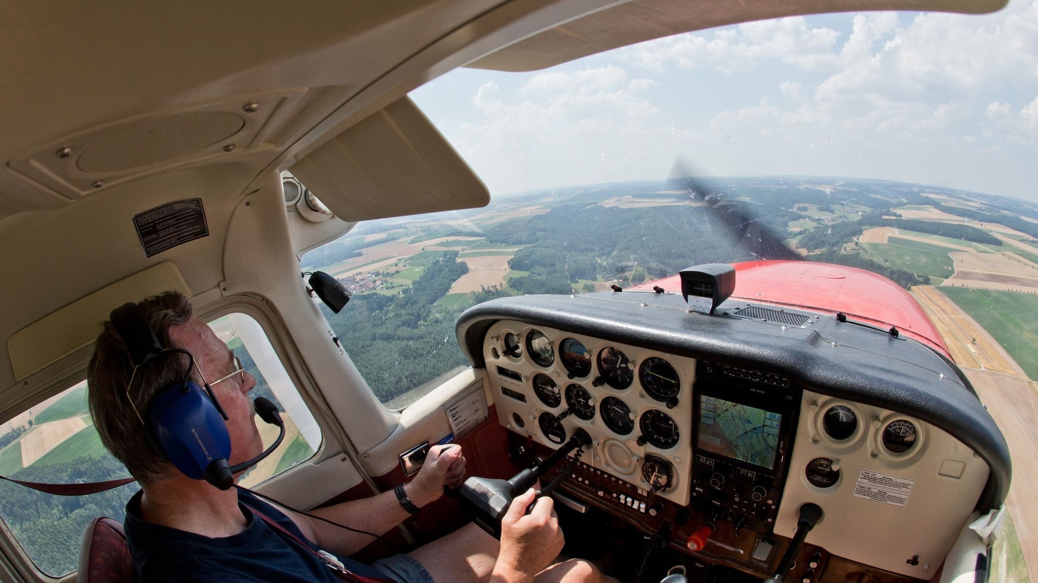 Ein Pilot sitzt im Cockpit einer Propellermaschine und überfliegt eine Landschaft. | Bild: picture alliance/dpa/Daniel Karmann Ein Pilot sitzt im Cockpit einer Propellermaschine und überfliegt eine Landschaft.